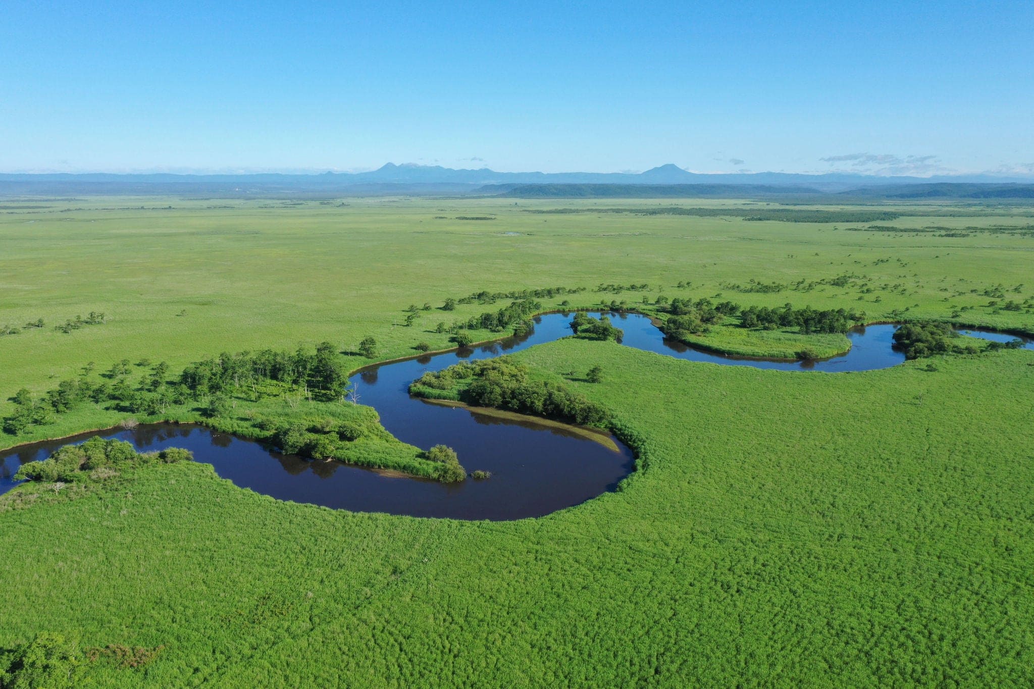 Kushiro River flowing through the Kushiro Marsh in summer in eastern Hokkaido Drone aerial photography Mt. Meakan Mt. Oakan