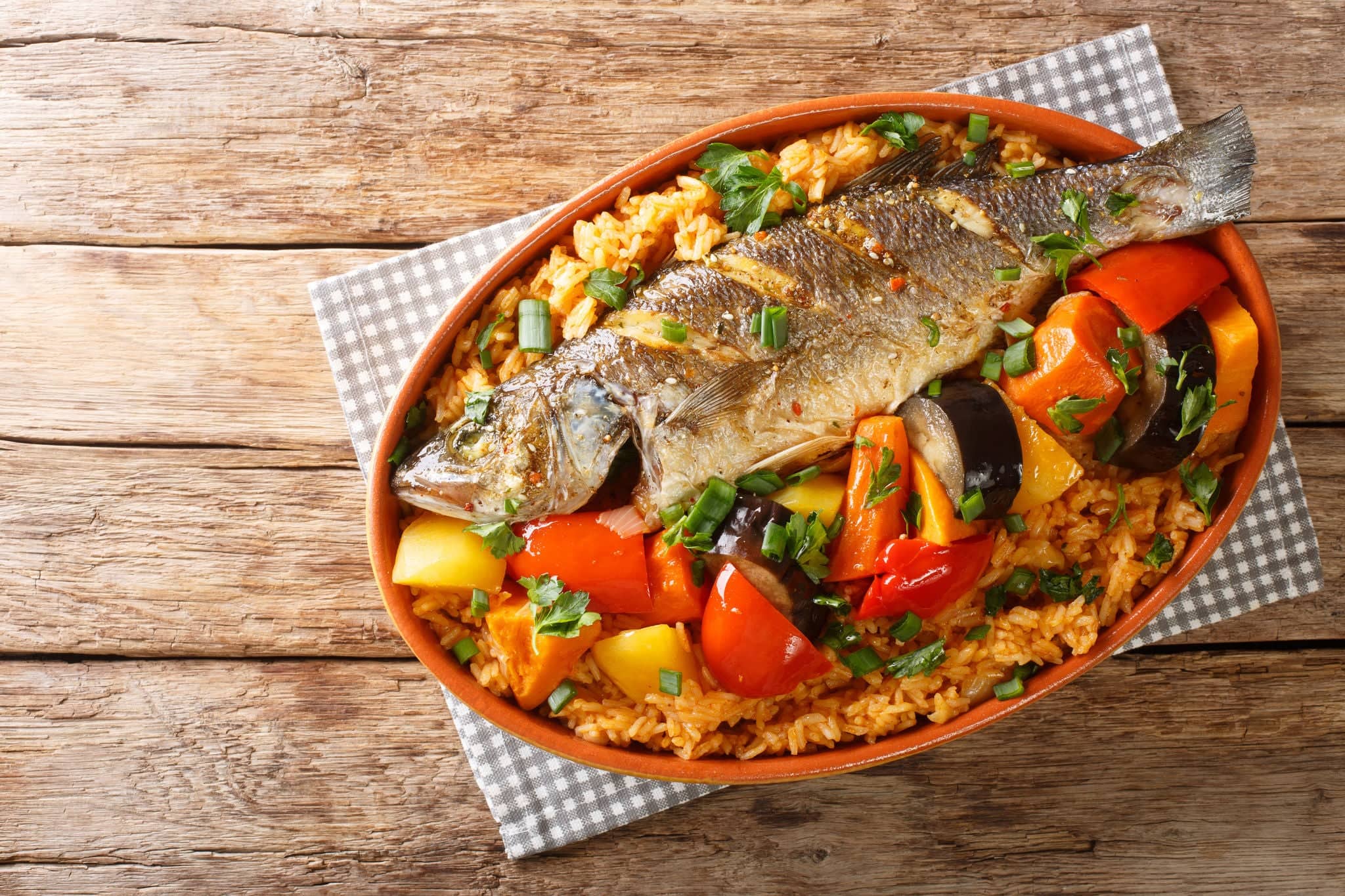One-pot Thieboudienne Traditional West African Fish and Rice Dish with vegetables closeup in the dish on the table. horizontal top view from above