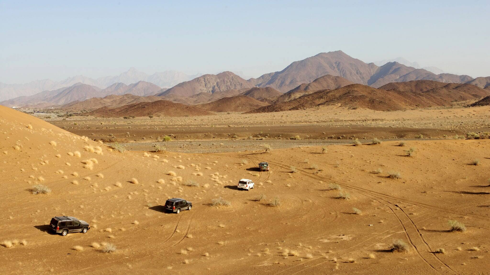 A convoy of 4x4 vehicles driving offroad in Oman.