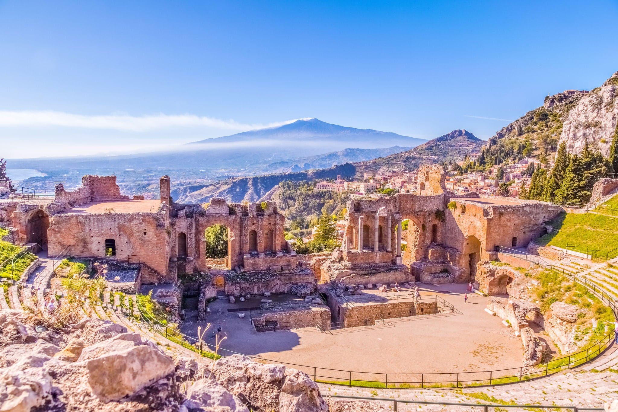 The Greek Theater of Taormina and smoking volcano Etna behind In burning sunshine, Sicily, Italy