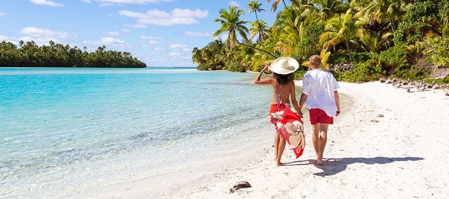 Couple holding hands, walking across the beach.