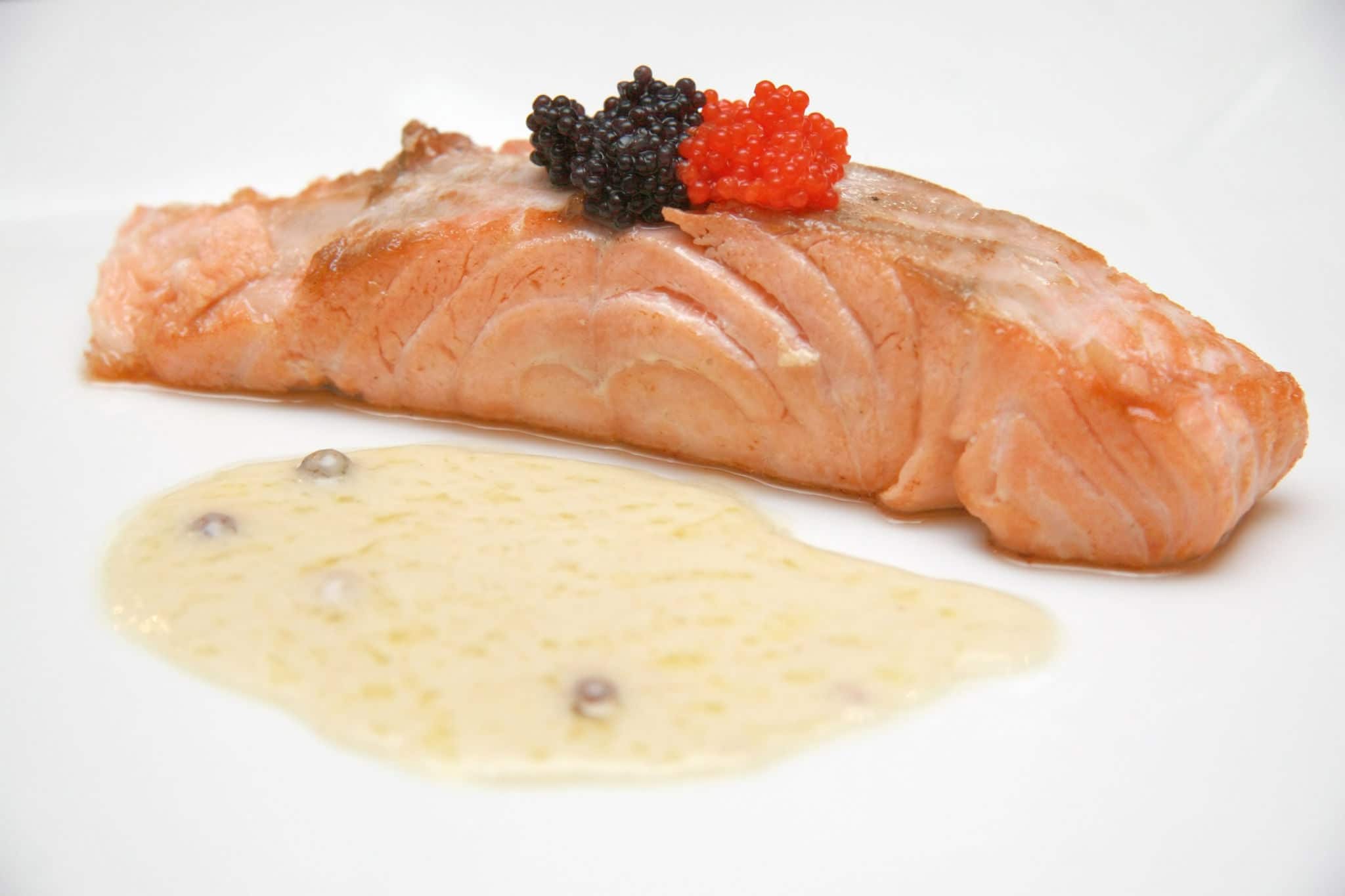 Smoked salmon slice with black and red caviar accompanied by a light butter and pepper sauce