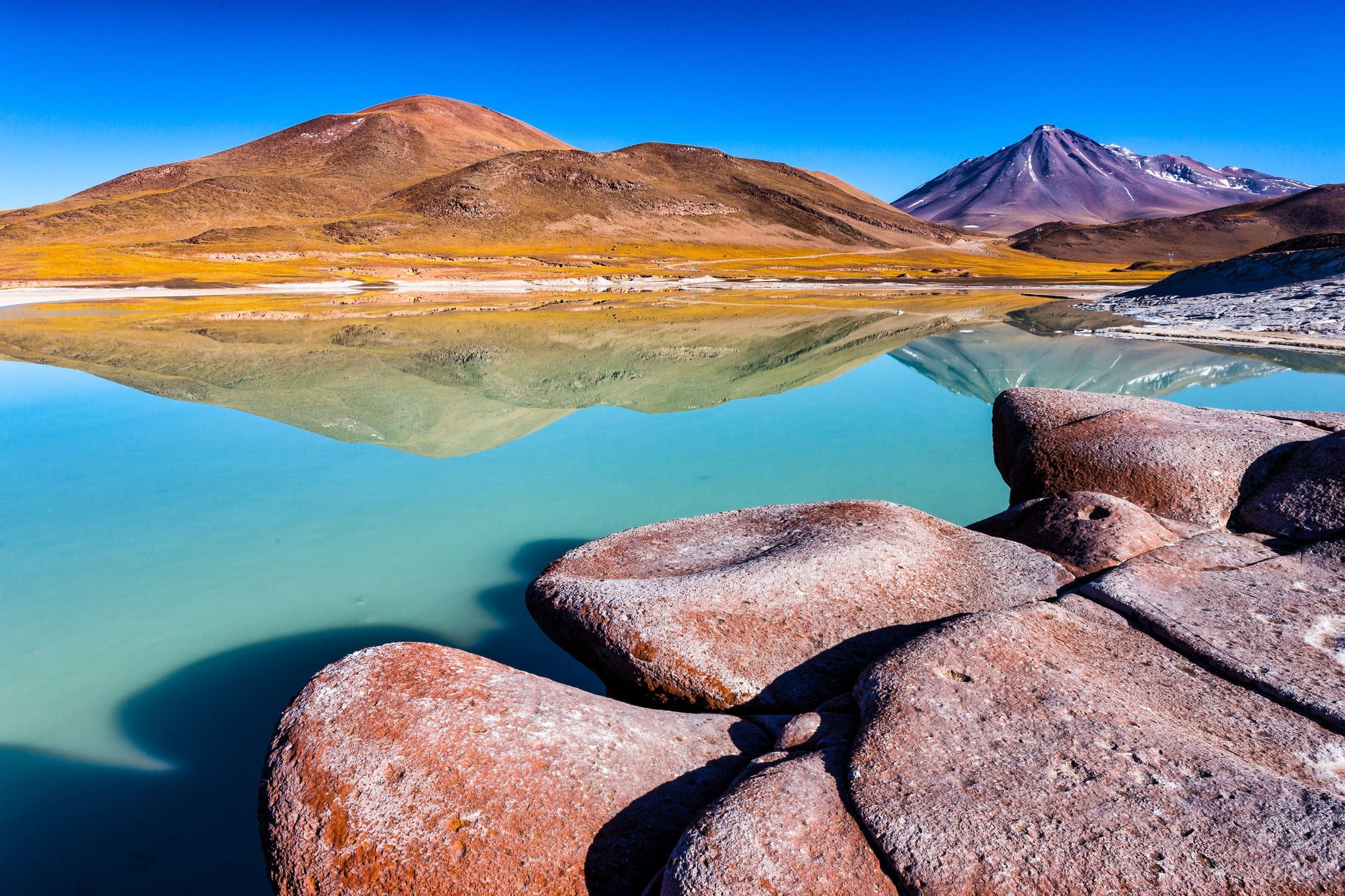 Piedras Rojas, Cerro Caichinque mirrored in the lake and Vulcano Miniques in background. Atacama, Chile.