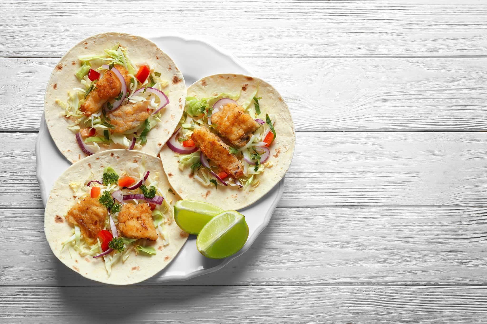 Plate with fish tacos on wooden table