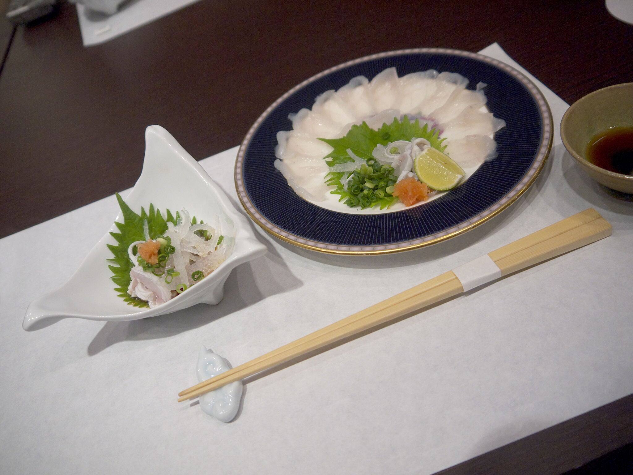 Fugusashi or Japanese fugu blowfish sashimi thin transparent slices on the plate decorated with shiso perilla leaves