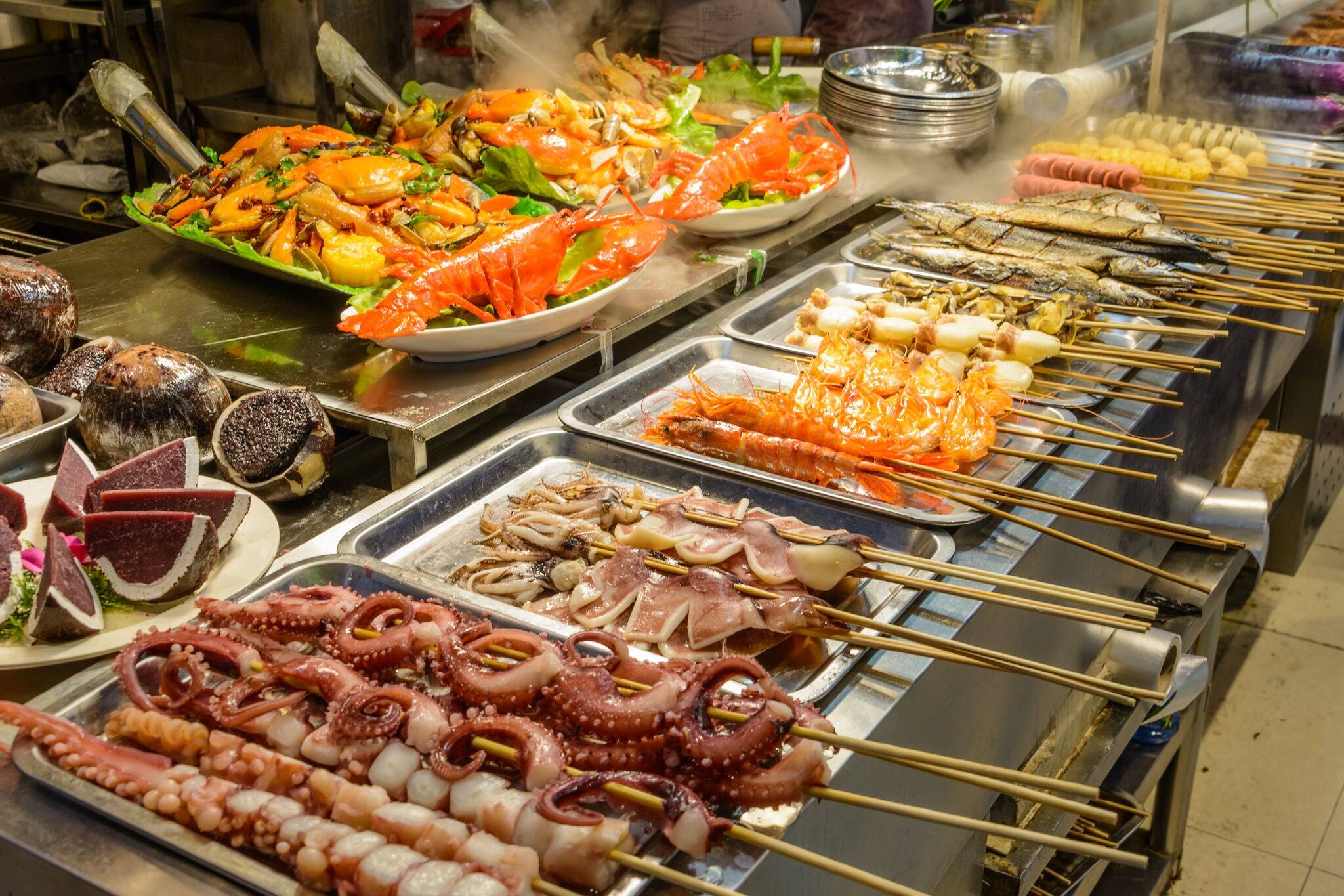 Chinese street food. Street trading. Chinese kinds of fresh seafood at an asian seafood market in Sanya, Hainan province, China. Inscription: name food.