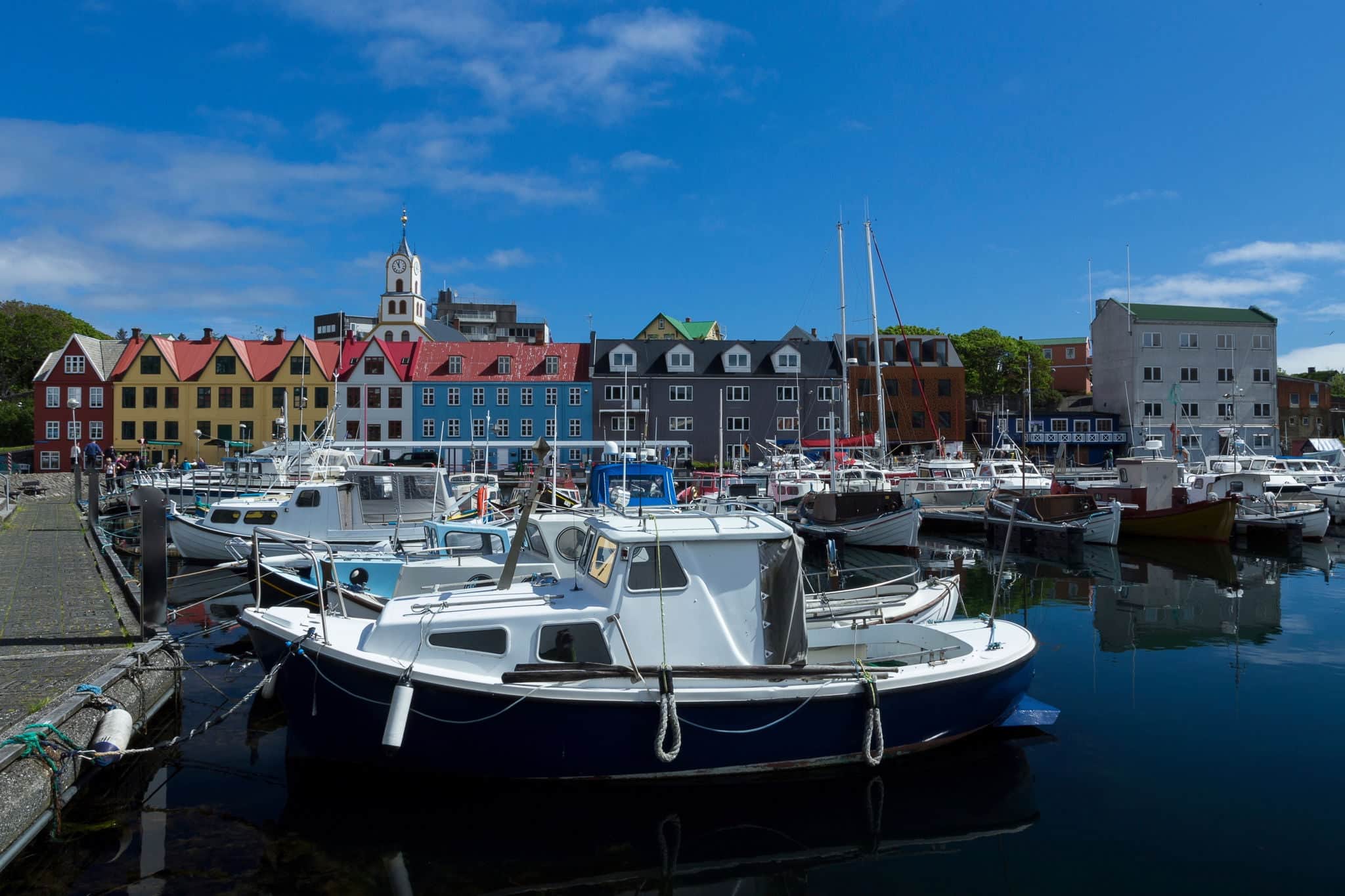Boats in marina, Torshavn, Streymoy Island, Faroe Islands, with colourful buildings and church in the background