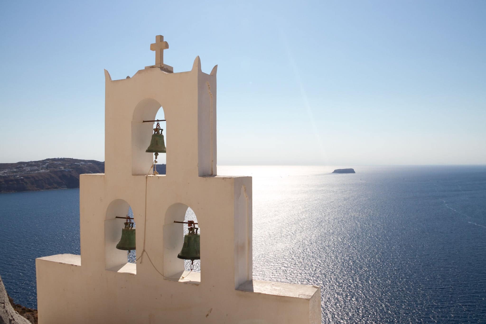 Orthodox church of Agios Nikolaos in Santorini island, Greece, bells, cross, sunny day and blue sea