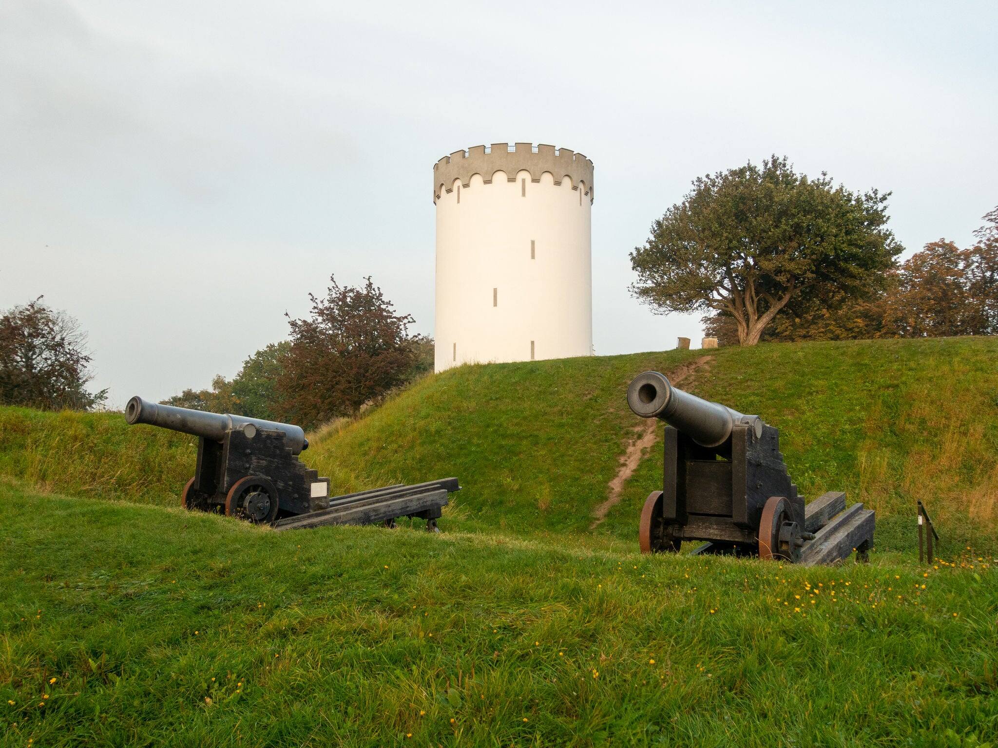 Old white water tower on rampart in city Fredericia, Denmark.Old bronze cannon on rampart in city Fredericia, Denmark.