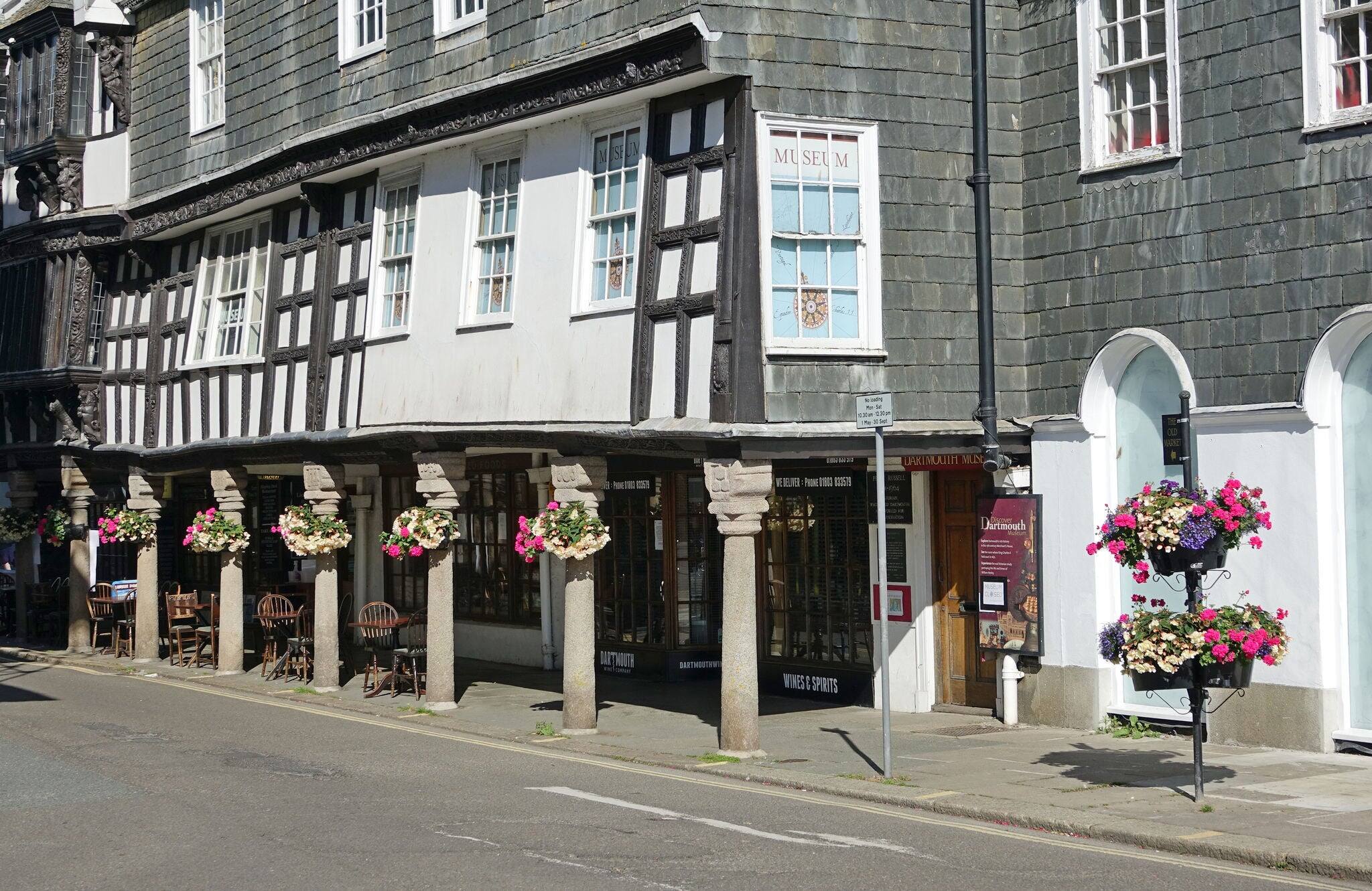Dartmouth Devon England. July 2020. The Butterwalk.  A Timbered framed arcade built circa 1635. Granite columns and carved headstones and flower baskets. No people.
