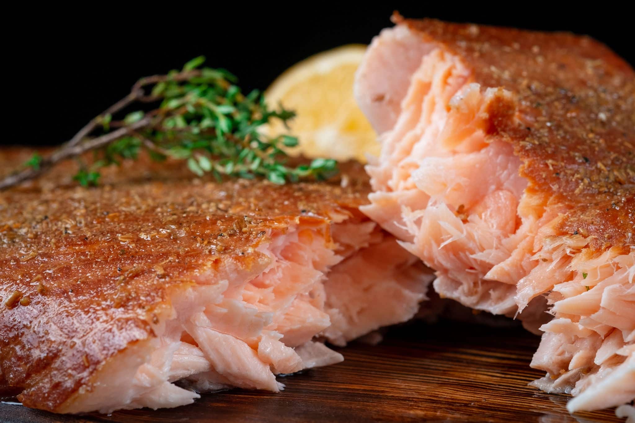 A half-torn piece of smoked salmon fillet on a wooden Board on a dark background