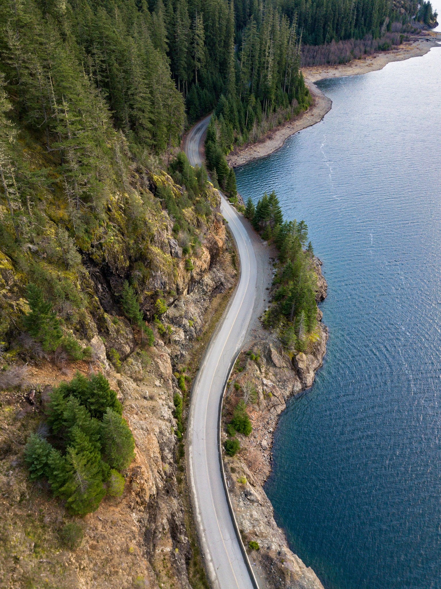 Drone ariel shot of the winding roads near Campbell River, BC. Winding roads along the coast line with beautiful tree's and ocean.