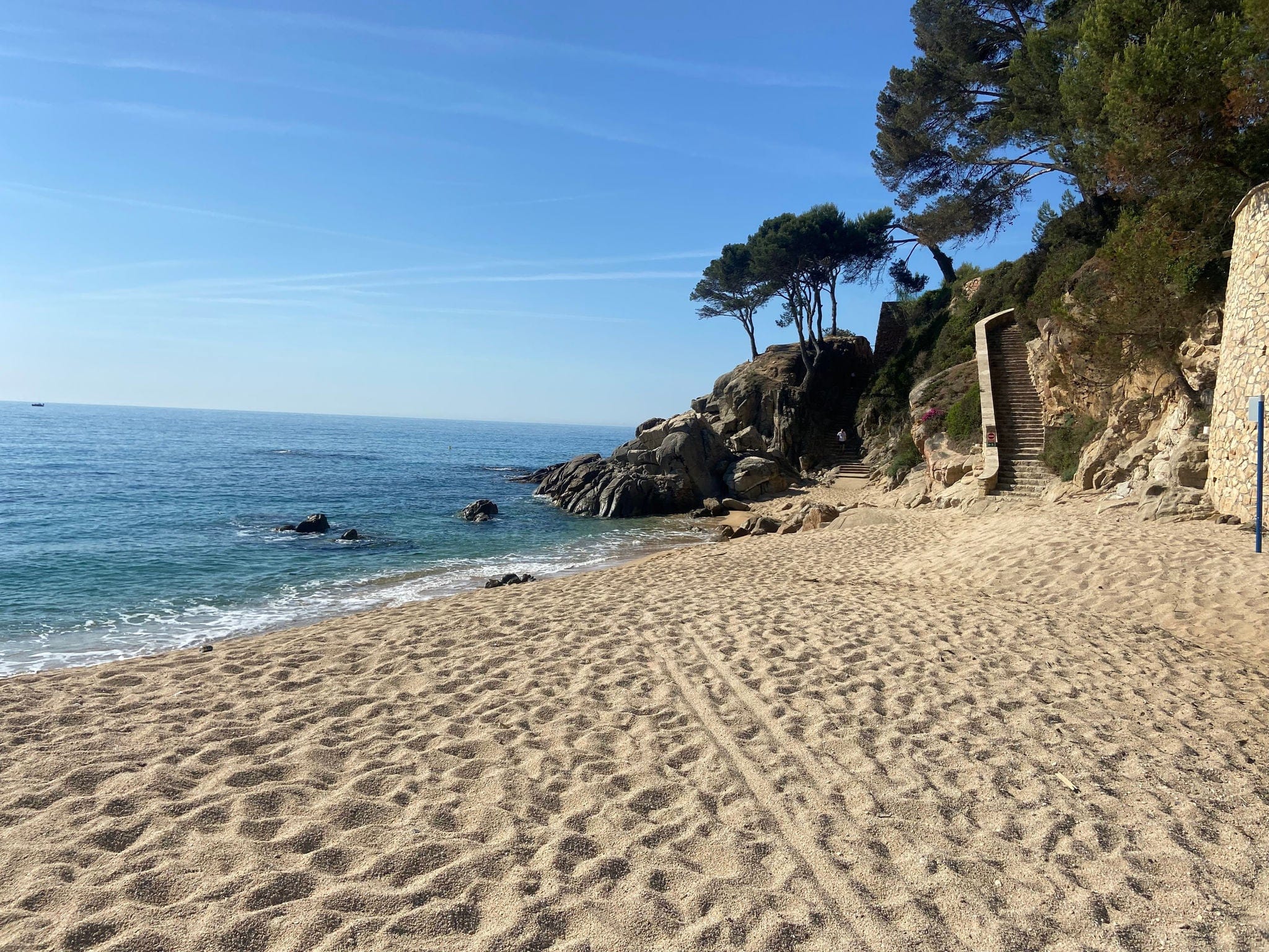 Stunning Costa Brava beach scene featuring golden sand and turquoise Mediterranean waters. The sun-drenched shoreline and clear, tranquil waves create a perfect setting for relaxation and fun