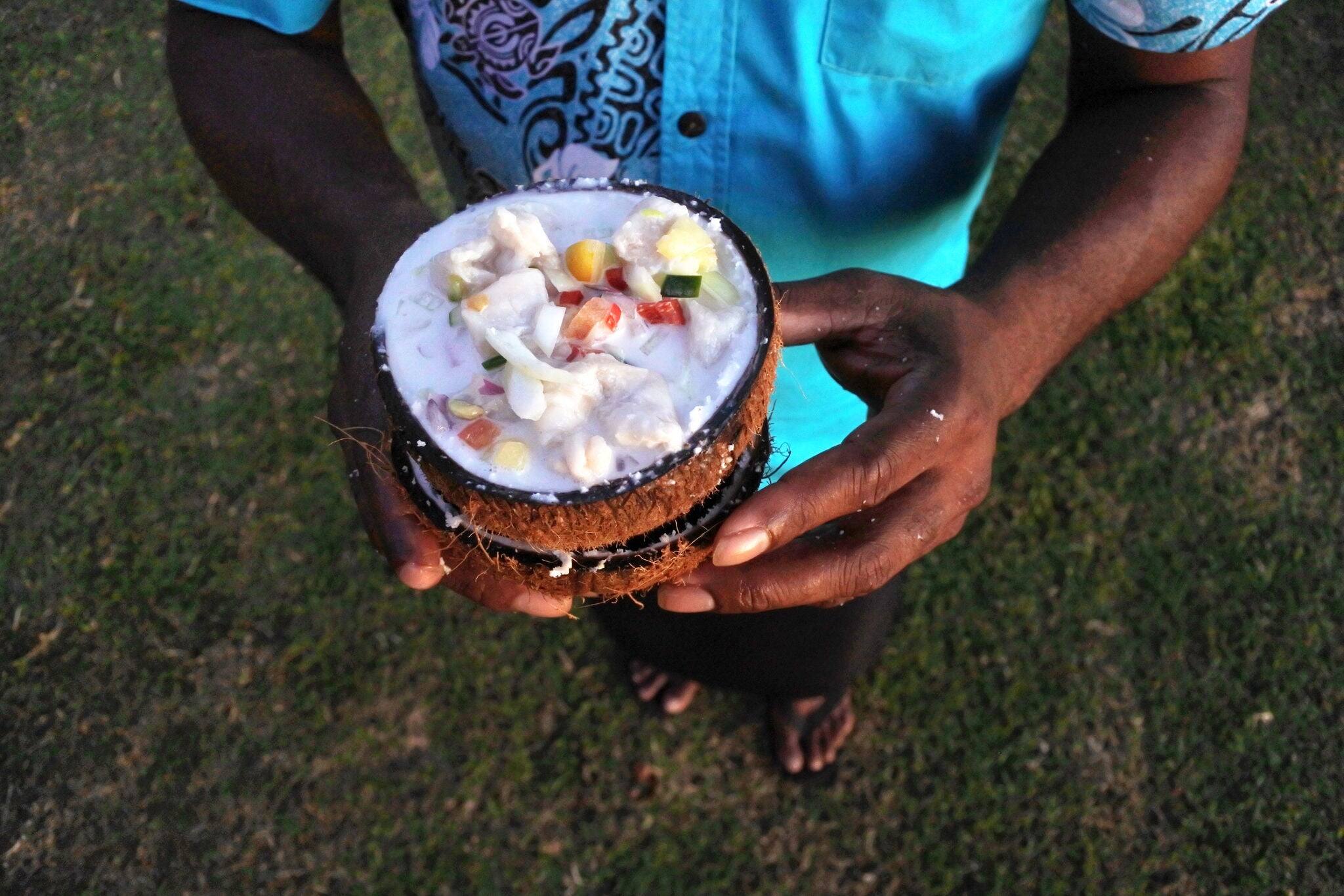 Above view of Indigenous Fijian man hands serves Fijian Food, Kokoda (Raw Fish Salad).Kokoda is Fiji's version of ceviche, enriched with coconut milk to balance out all the acid.Real people.Copy space
