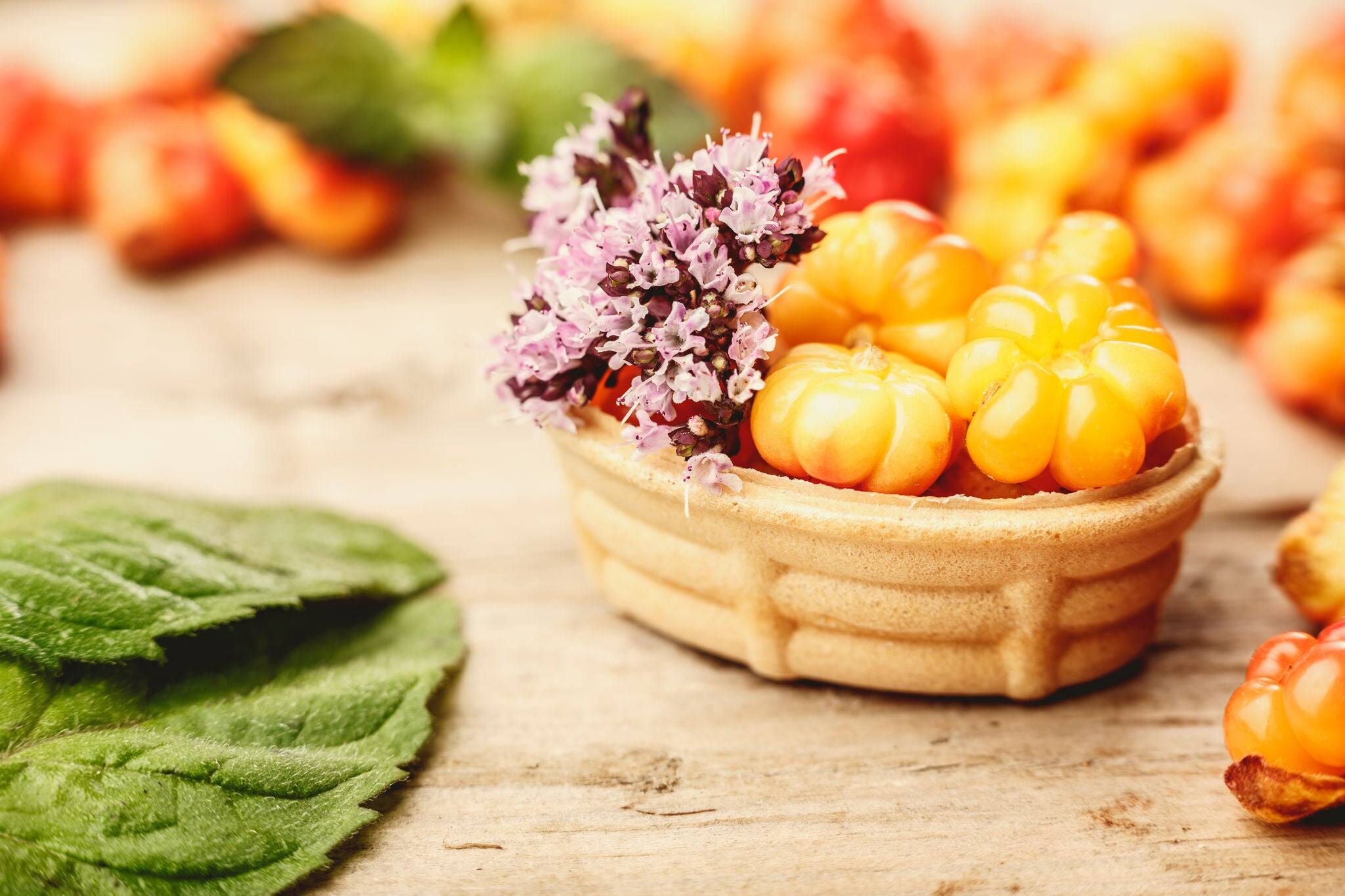 Cloudberry tart decorated with wild marjoram. Sweet baked dessert with fresh wild cloudberries on a wooden table. Instagram filter styled