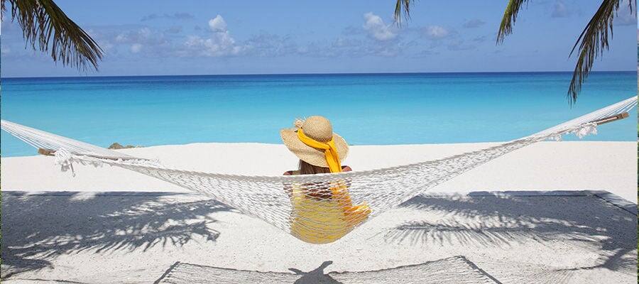 Woman relaxing in hammock on beach.