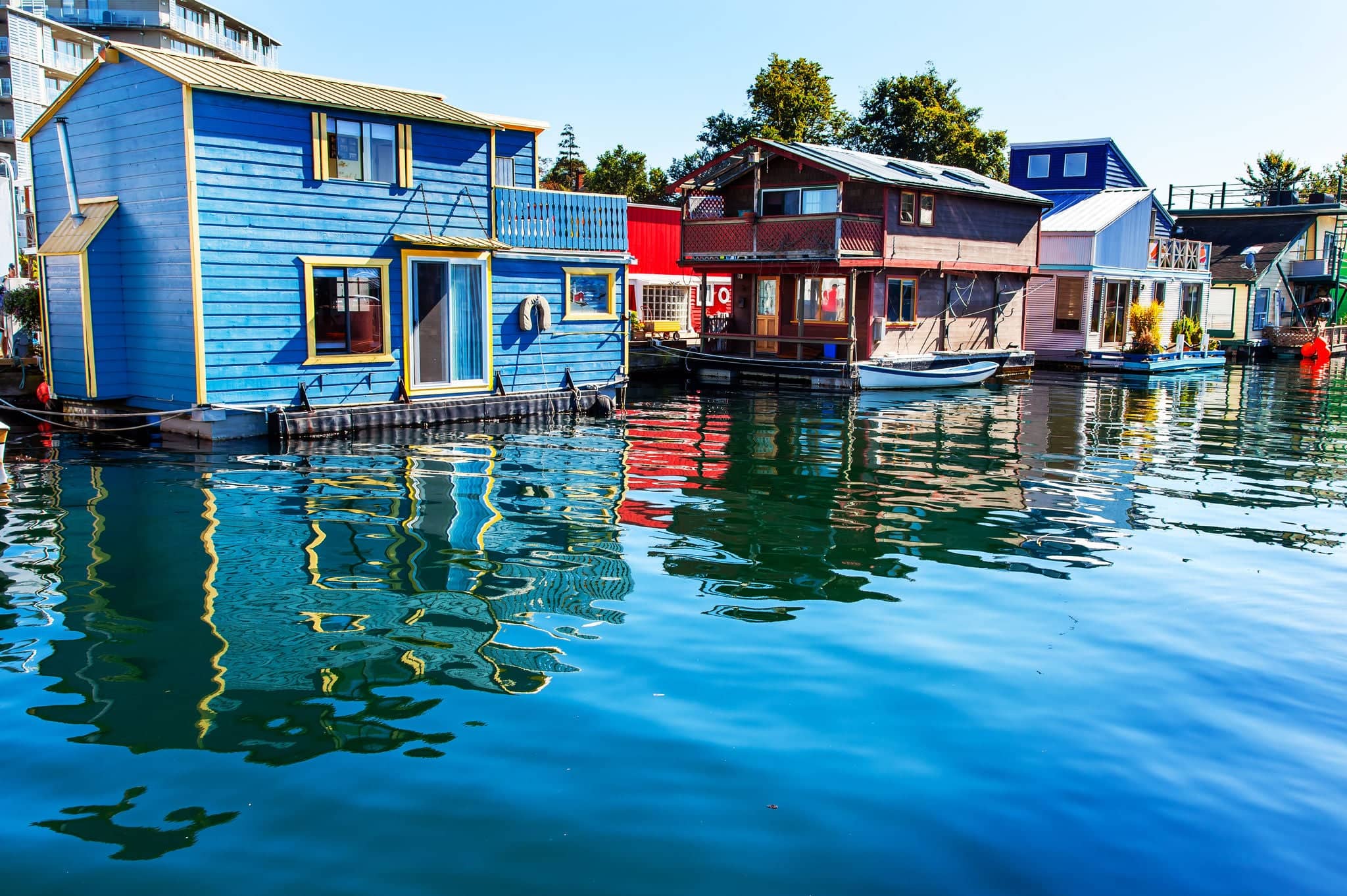 Floating Home Village Blue Red Brown Houseboats Fisherman's Wharf Reflection Inner Harbor, Victoria British Columbia Canada Pacific Northwest.  Area has floating homes, boats, piers, and restaurants.