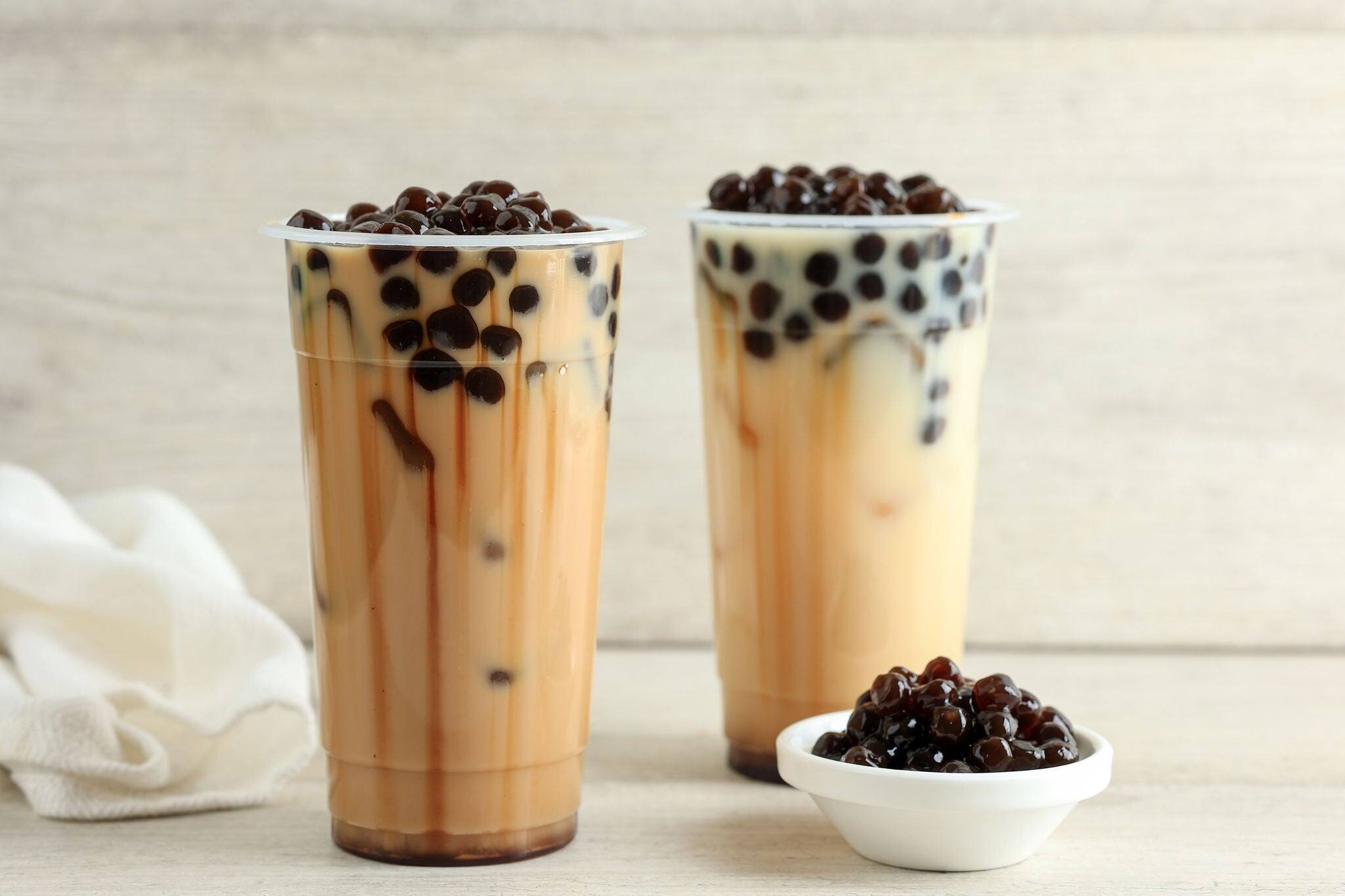 Taiwan Milk Tea with Boba Bubble Pearl on Plastic Disposable Cup, on Wooden Background