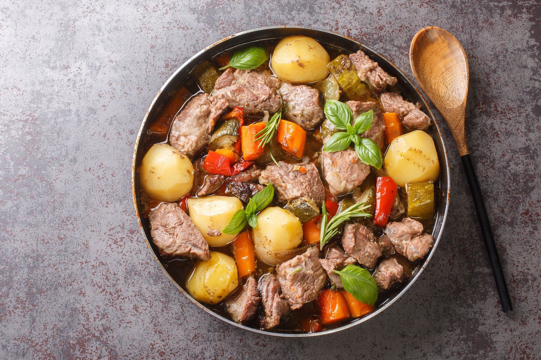 Traditional croatian dish Peka view, meat and vegetables in iron cover under warm glow close-up on the table. horizontal top view from above