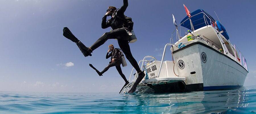 Two divers jumping into sea for dive.