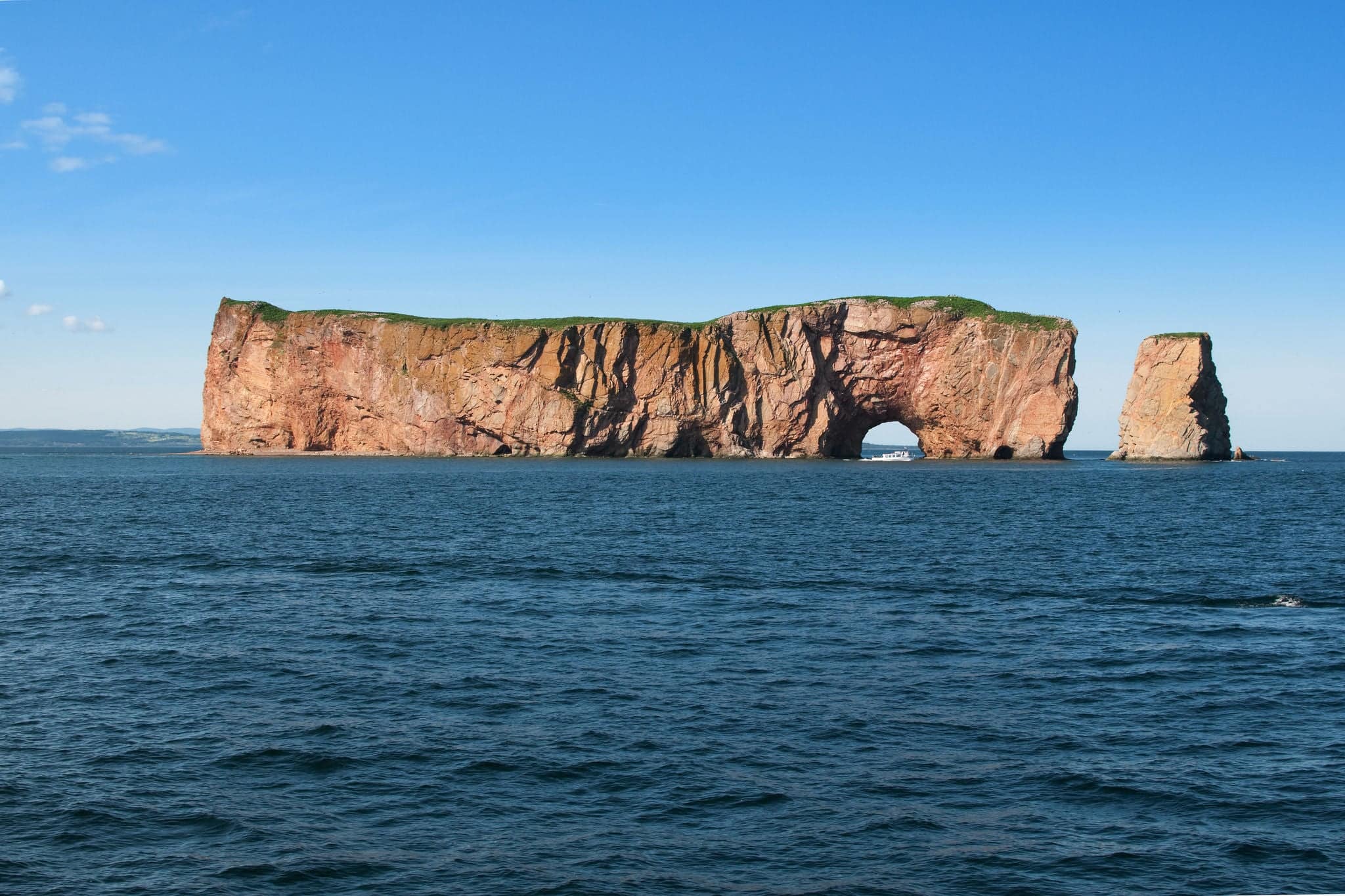 Perce rock, Gaspesie, with boat passing in front of the hole