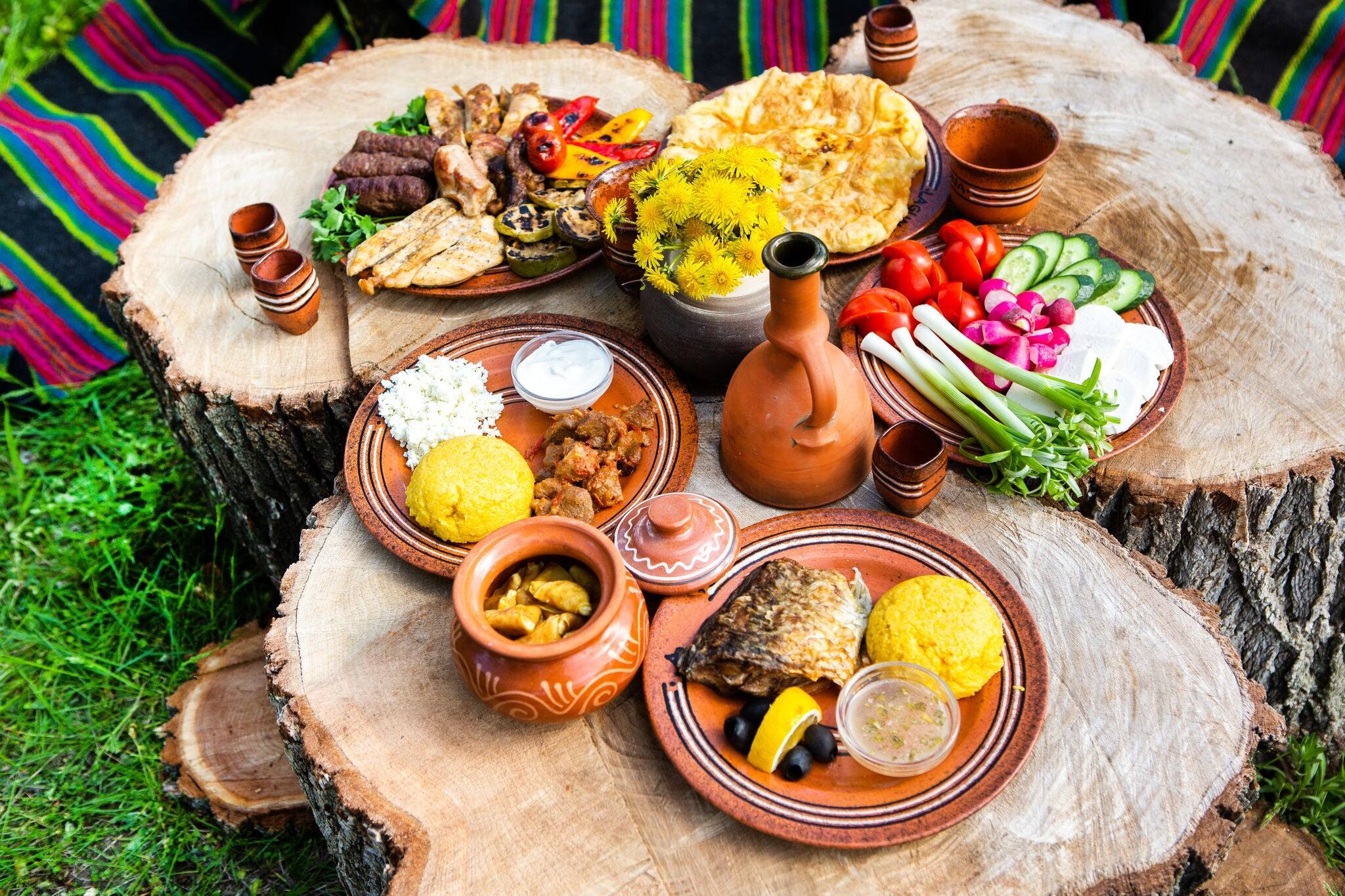 Homemade Romanian Food with grilled meat, polenta and vegetables Platter on camping. Romantic traditional moldavian food outside on the wood table.