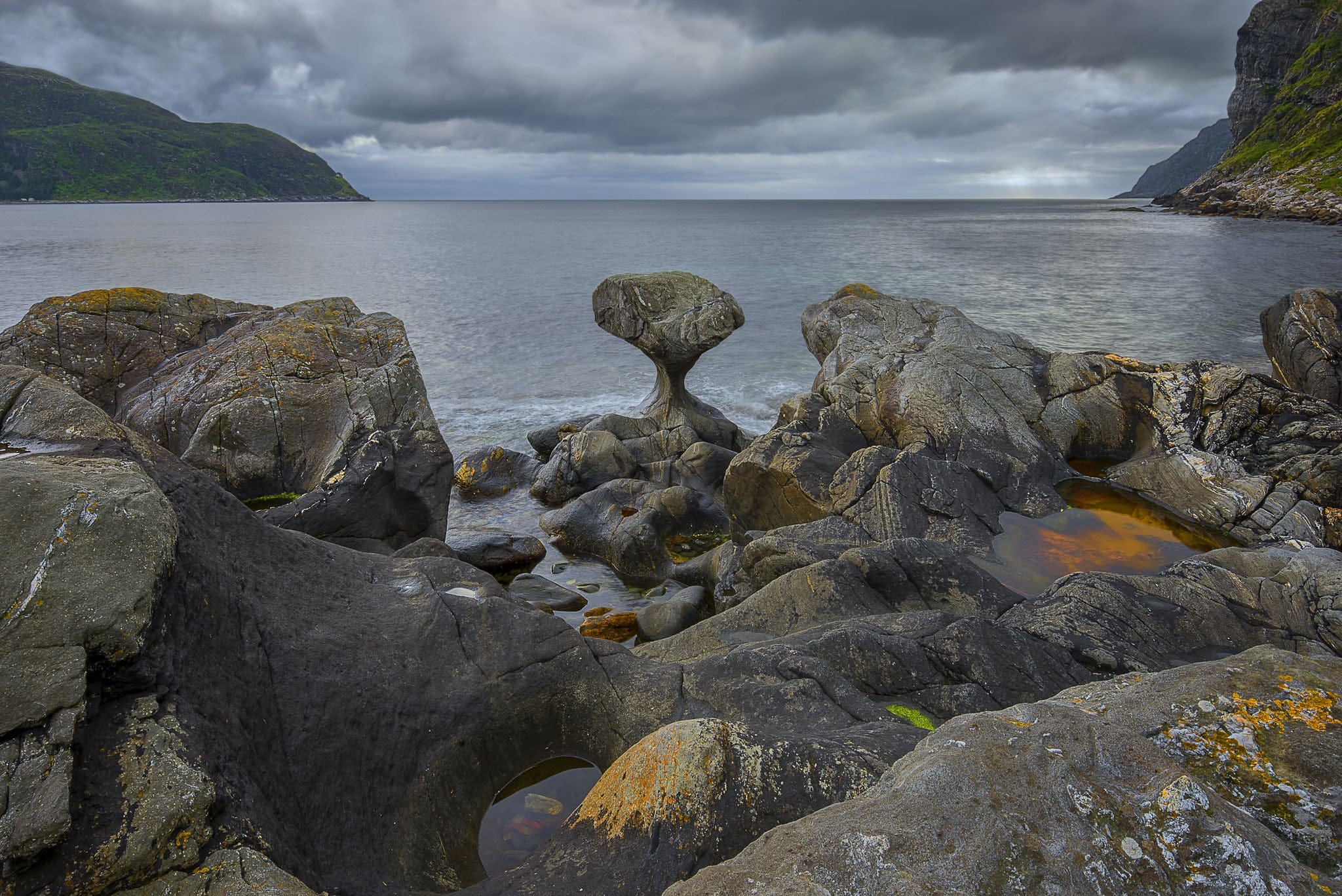 Norway, Unusual stone in Atlantic ocean coast. View on Kannesteinen and Kvalheimsvika. Over thousands of years, ocean waves have ground the rock to the special shape it has today. black and white