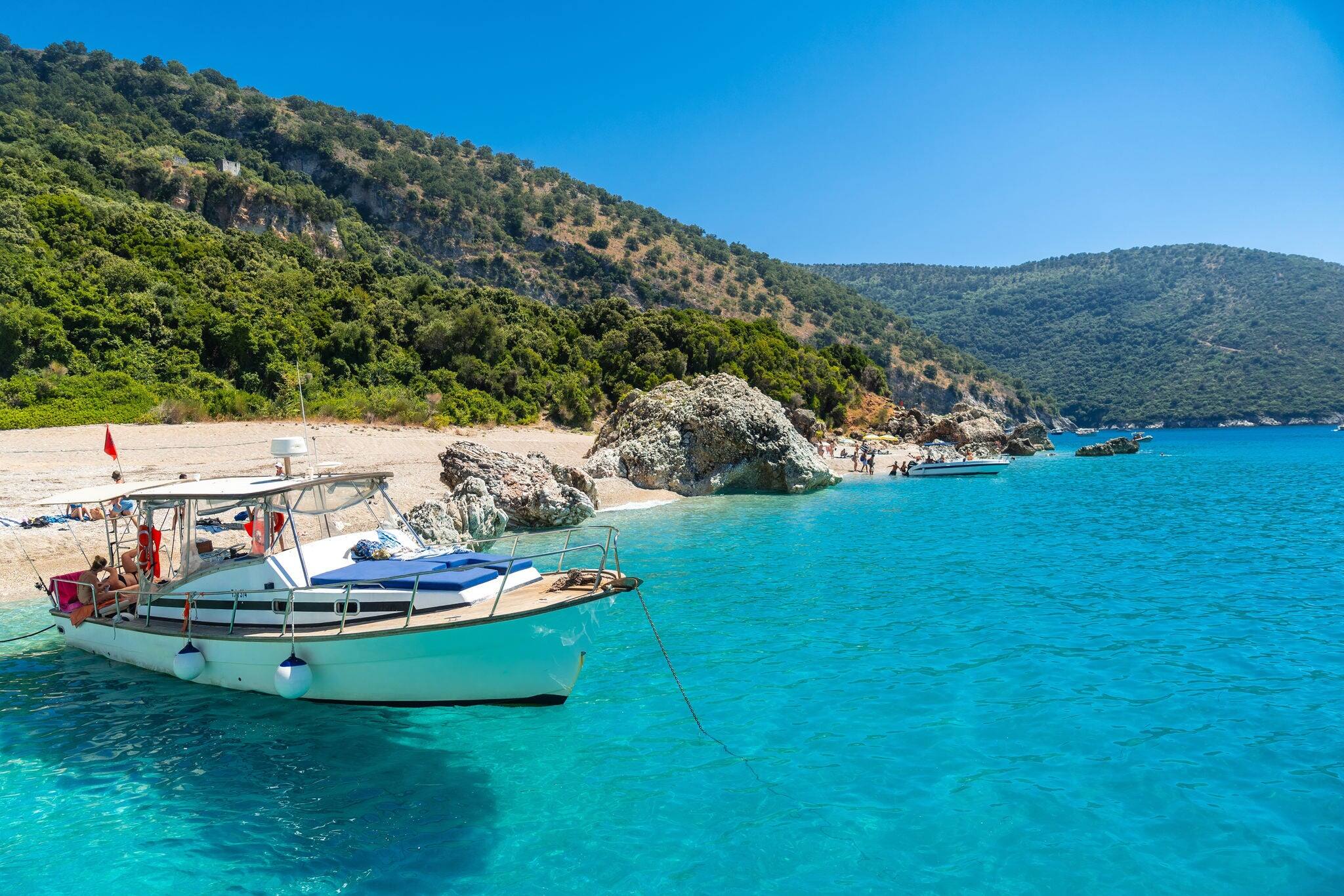 Boat in the transparent waters of the paradise beach of Kroreza or Krorez from the boat on the Albanian riviera in Sarande, Albania