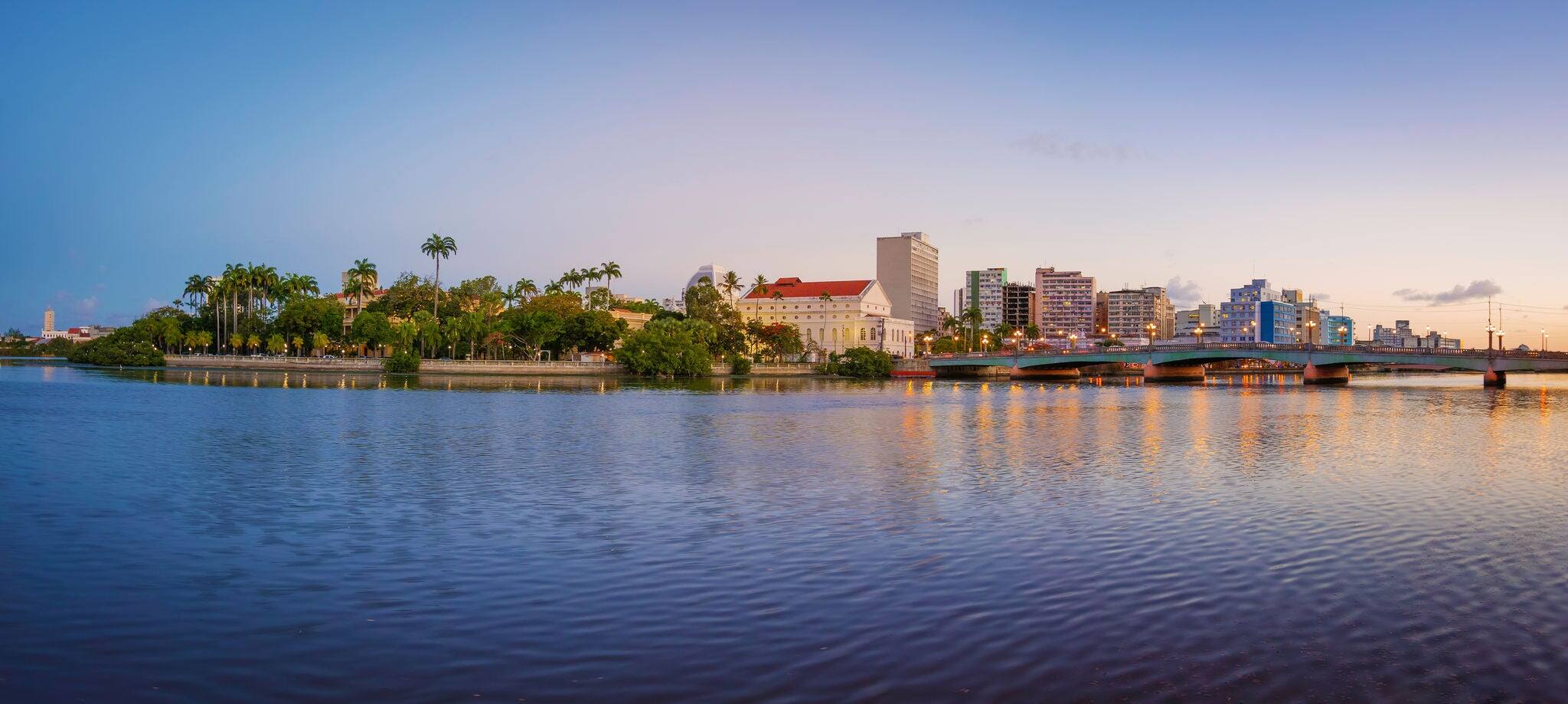 The skyline of the historic city of Recife in Pernambuco, Brazil by the Capibaribe river at sunset.