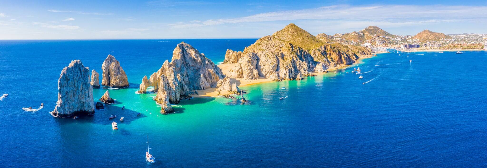 Aerial panoramic view of Lands End and El Arco at the tip of Baja California Sur, with the Cabo San Lucas, Mexico marina in the background