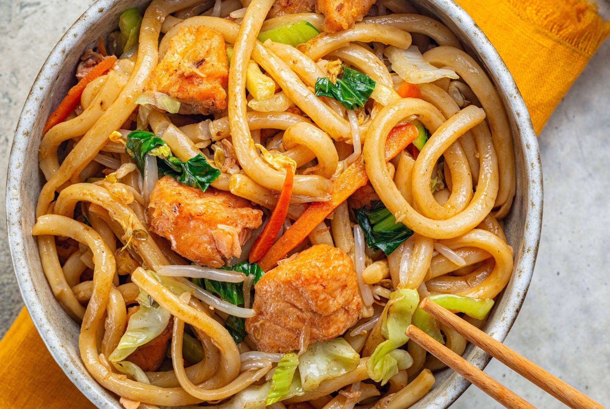 Stir Fried Yaki Udon Noodles with Salmon Fish, Vegetables and Soy-based Sauce. Japanese food. Top view.