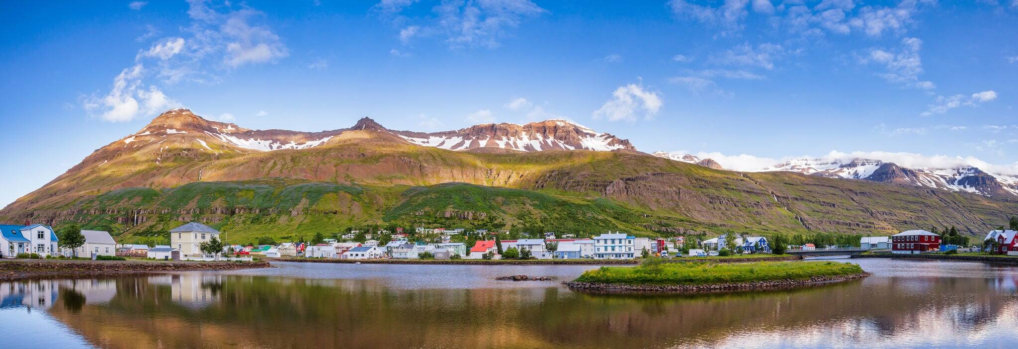 Panoramic view of Seydisfjordur with houses and surrounding landscape reflecting in Fjardara lake. Seydisfjordur is a small picturesque town and port at Seydisfjordur fjord in Eastern Iceland