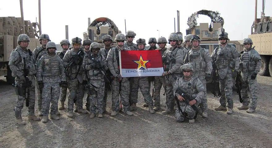 Military members holding the Honor and Remember flag