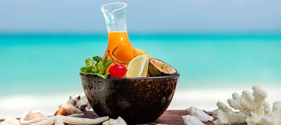 Bowl of fruit with fresh fruit juice with the sea in the background.