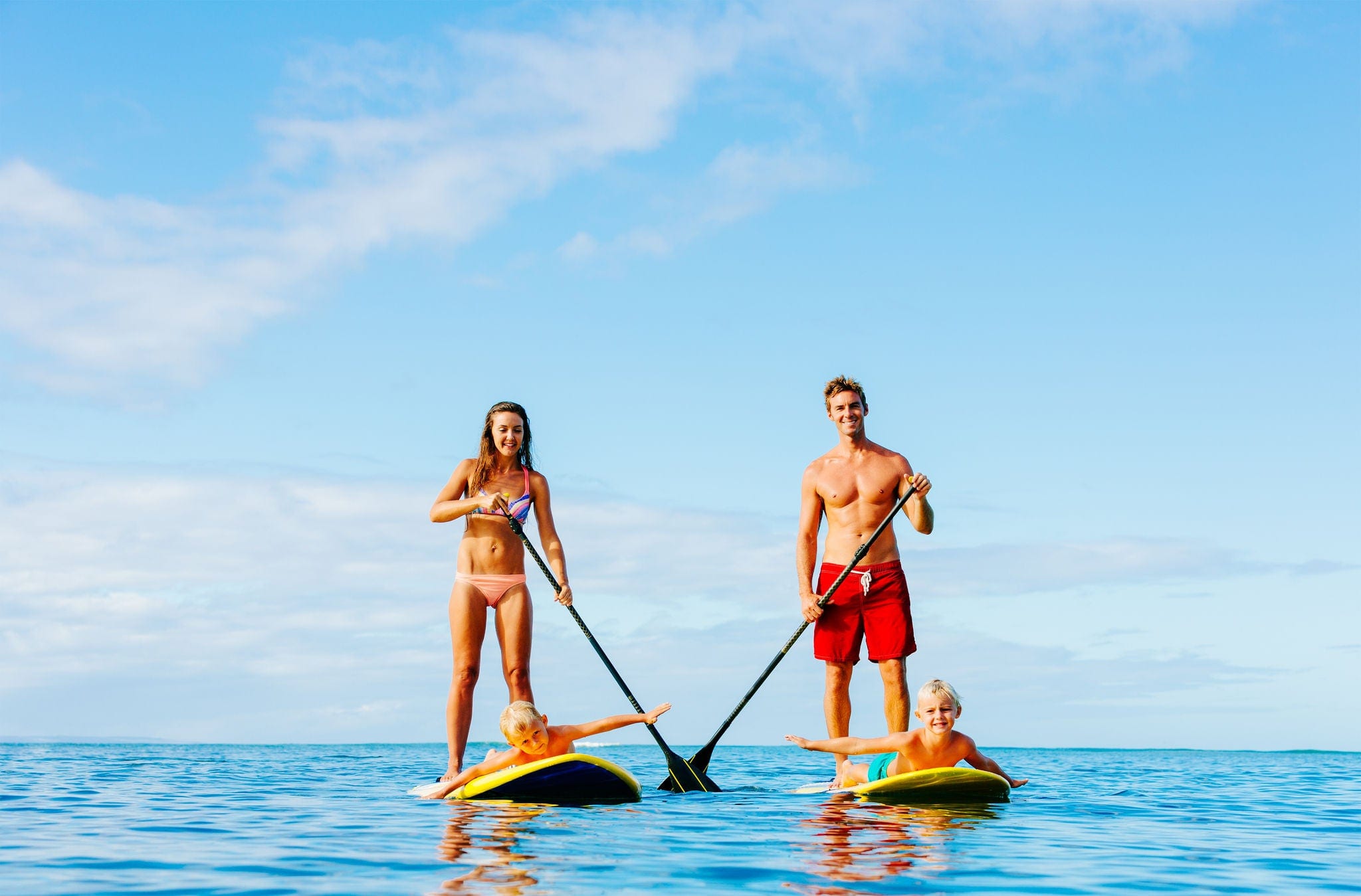Family Having Fun Stand Up Paddling Together in the Ocean on Beautiful Sunny Morning