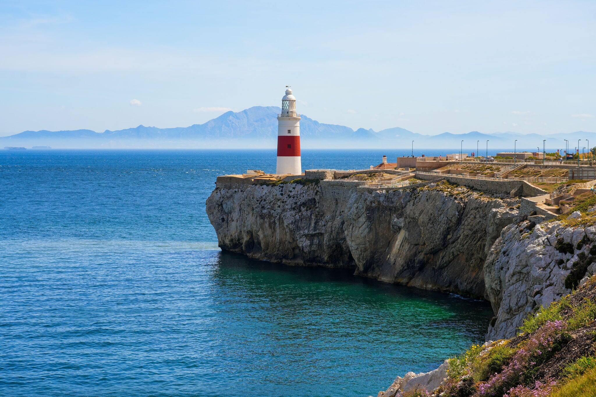 Europa Point Lighthouse facing the strait of Gibraltar on top of sea cliffs with the mountains of Morocco on the distance
