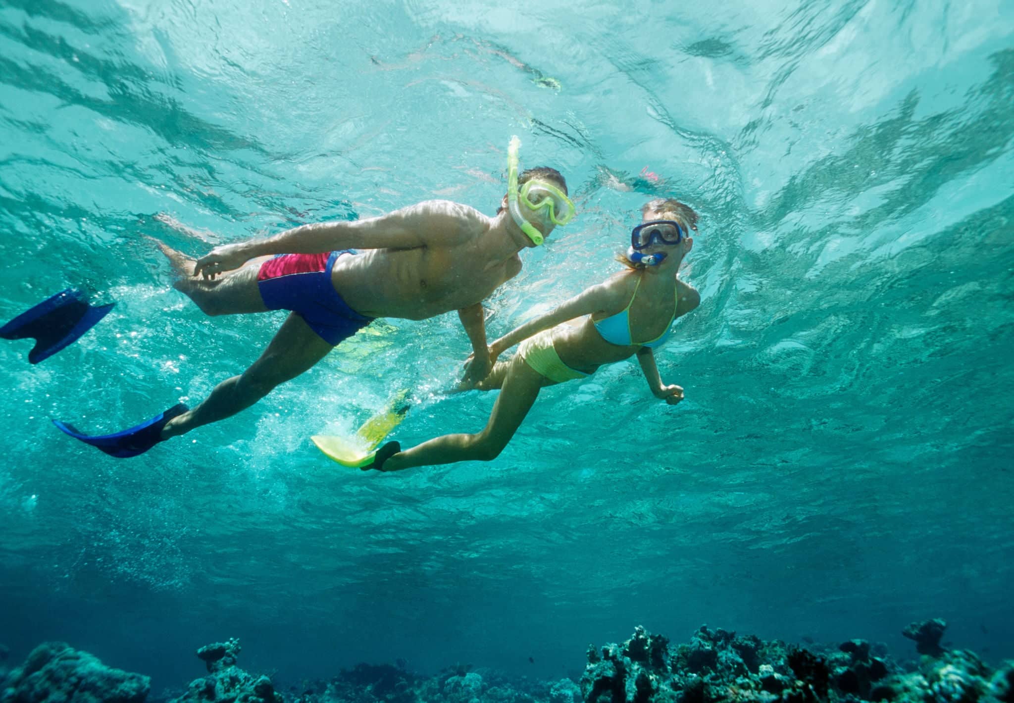 Young couple snorkelling above a shallow reef, underwater view.
