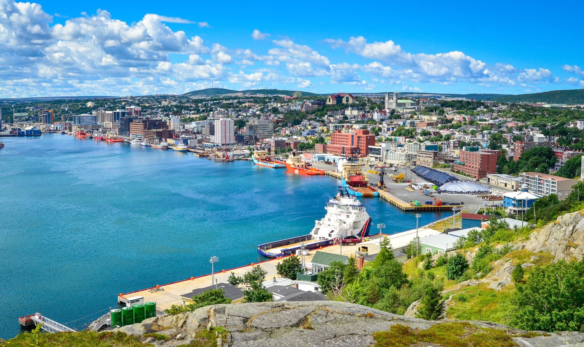 Panoramic views with bight blue summer day sky with puffy clouds over the harbor and city of St. John's NewFoundland, Canada.