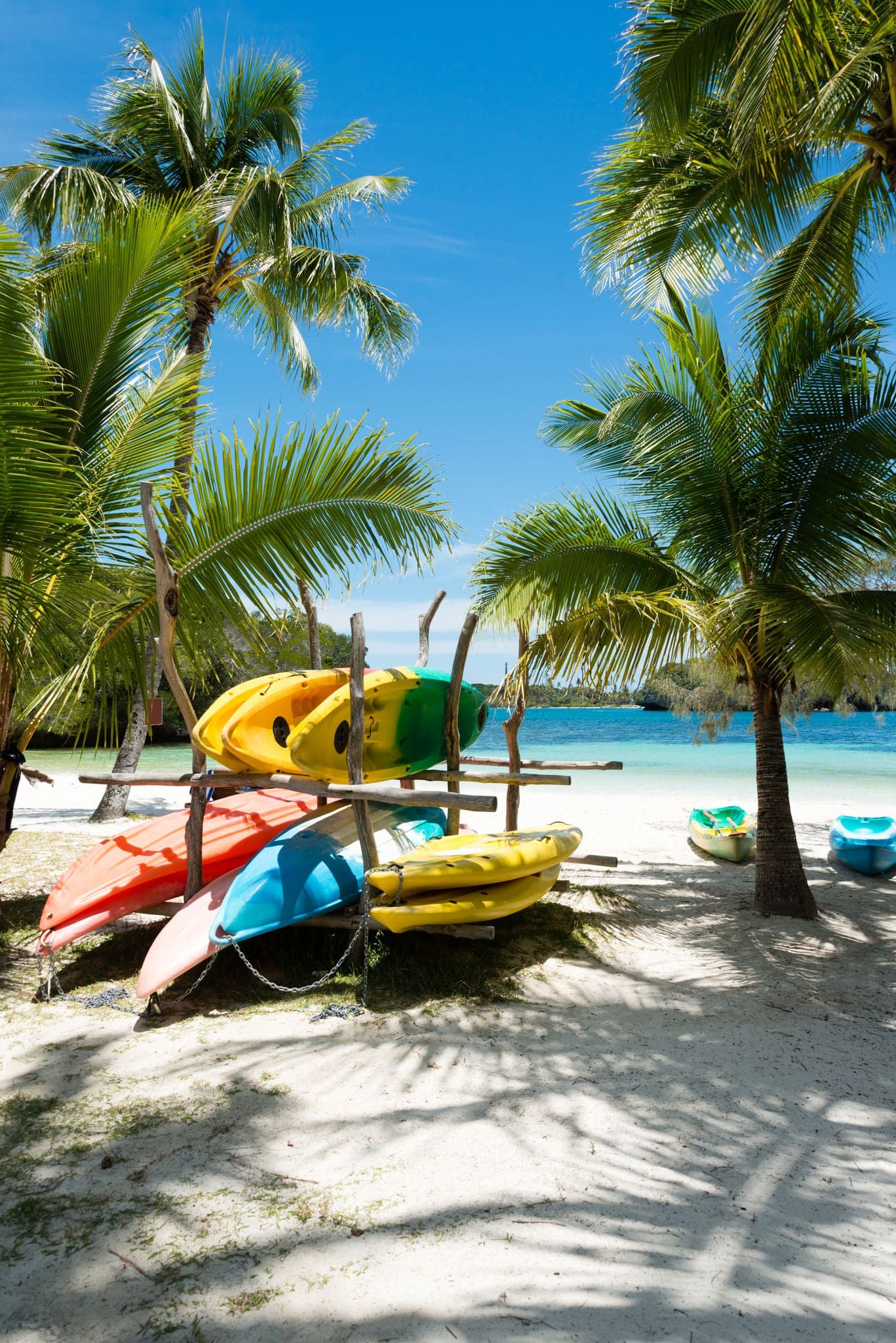 Colorful sea kayaks stacked on the beach of the Isle of Pines in New Caledonia