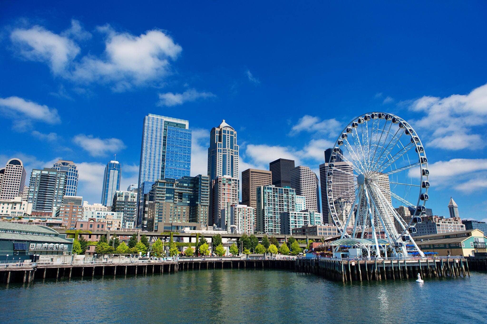 Seattle Ferris wheel, skyline and waterfront in sunny day with blue sky and clouds. The great wheel in Seattle downtown.