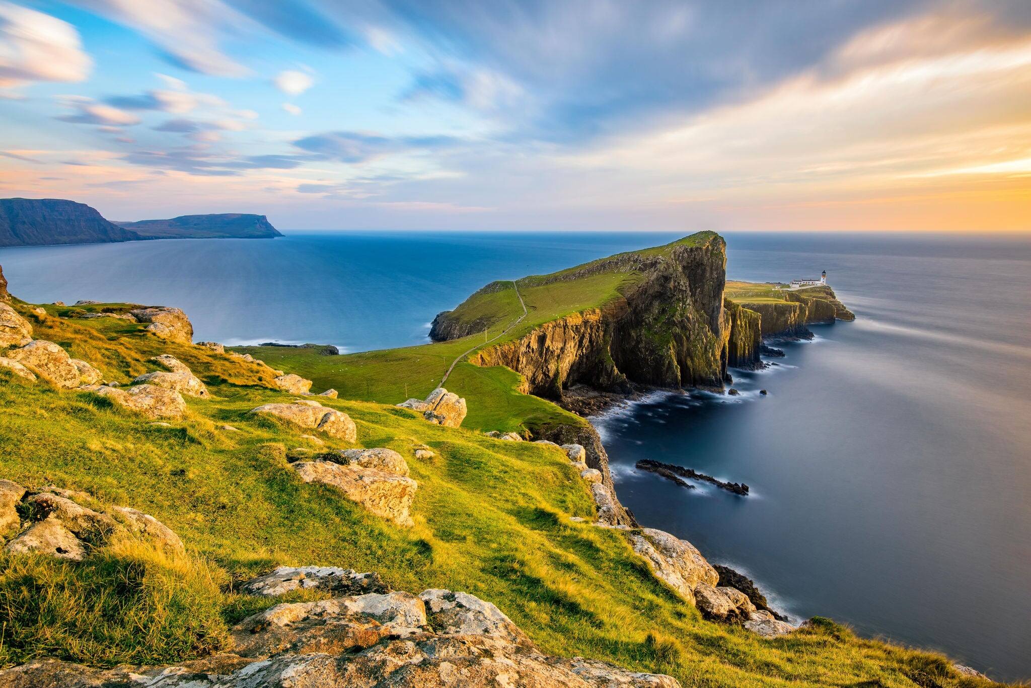 Neist Point Lighthouse on the Isle of Skye bathed in golden light from the setting sun.