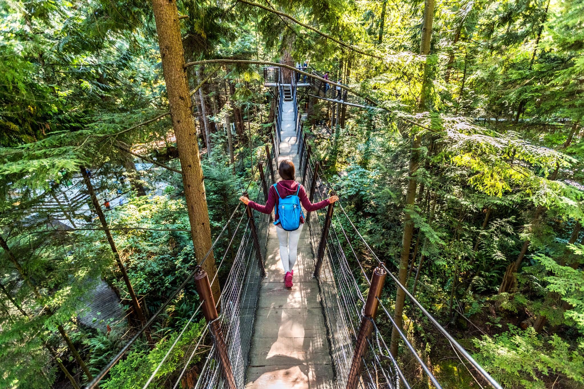 Mujer turística que viaja por Canadá caminando en la famosa atracción Capilano Suspension Bridge en el norte de Vancouver, Columbia Británica, destino turístico de vacaciones en Canadá.
