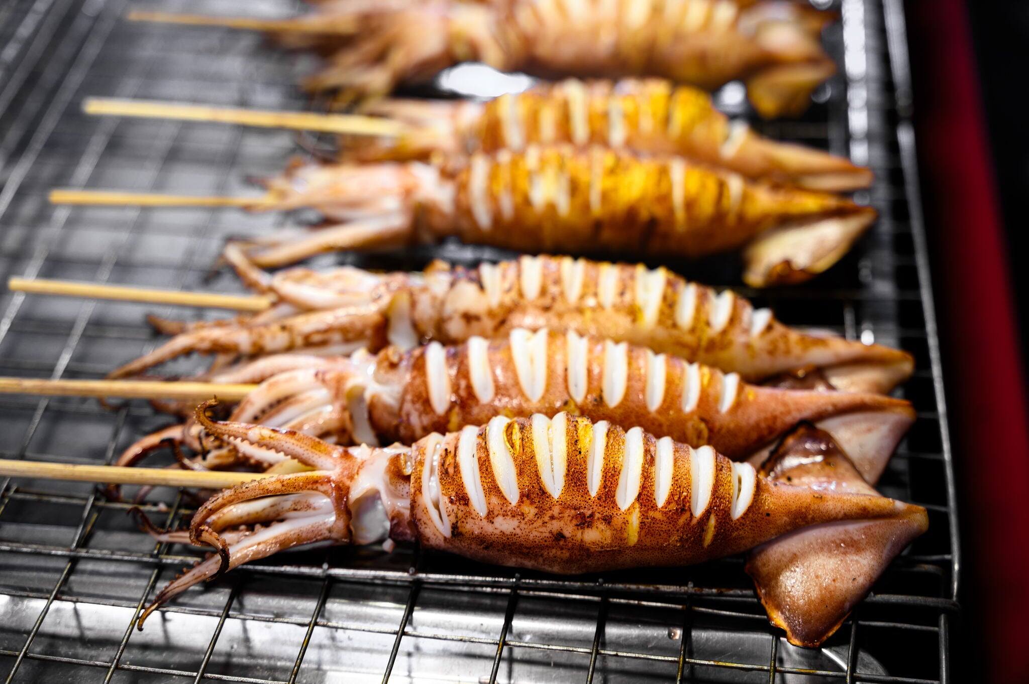 Grilled squid skewers on a charcoal stove in street food market