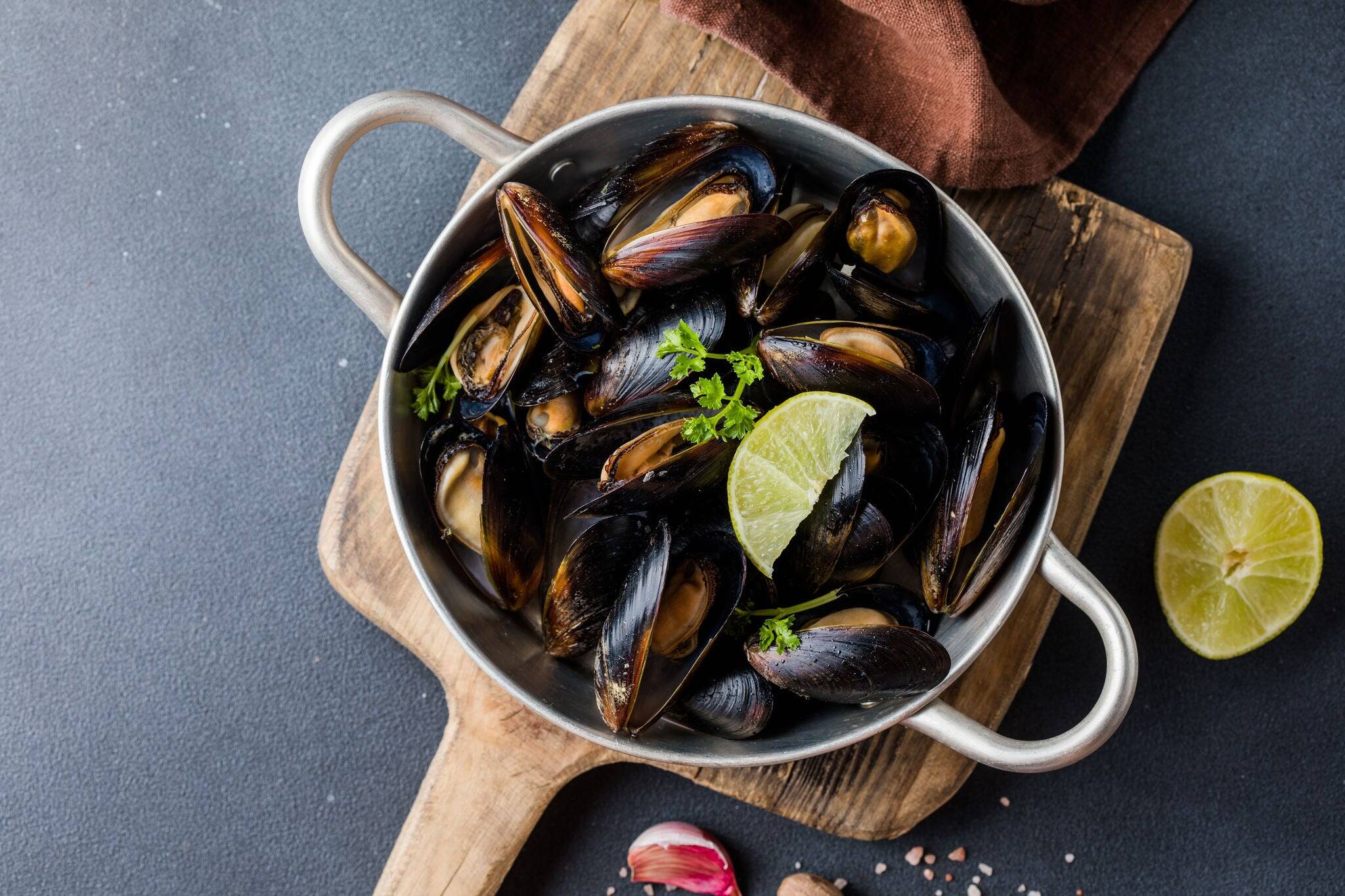 Seafood. Shellfish mussels. Baked mussels on cast iron black plate