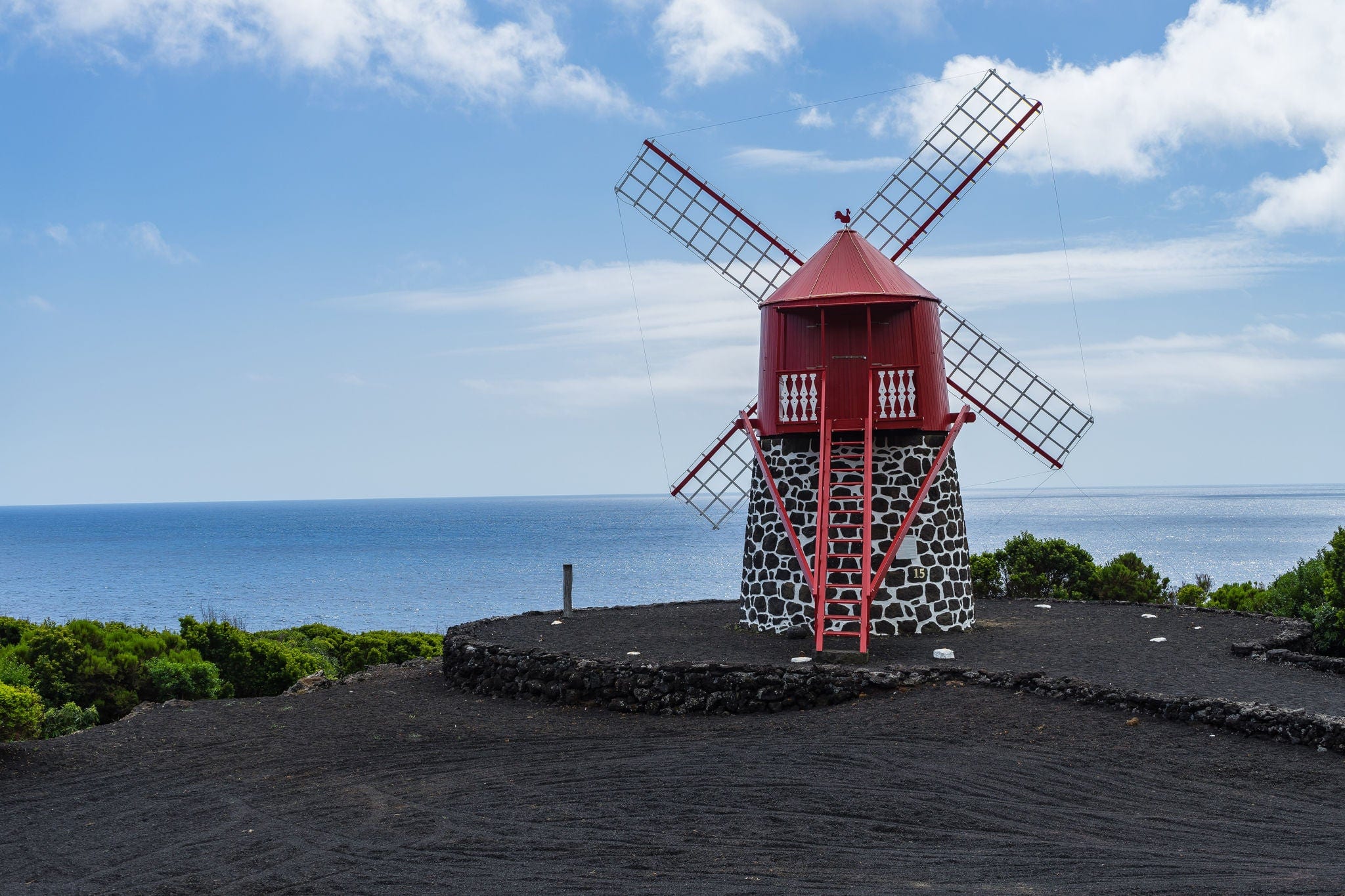 Seascape with scenic red windmill on the coast of Pico Island, Azores, Portugal