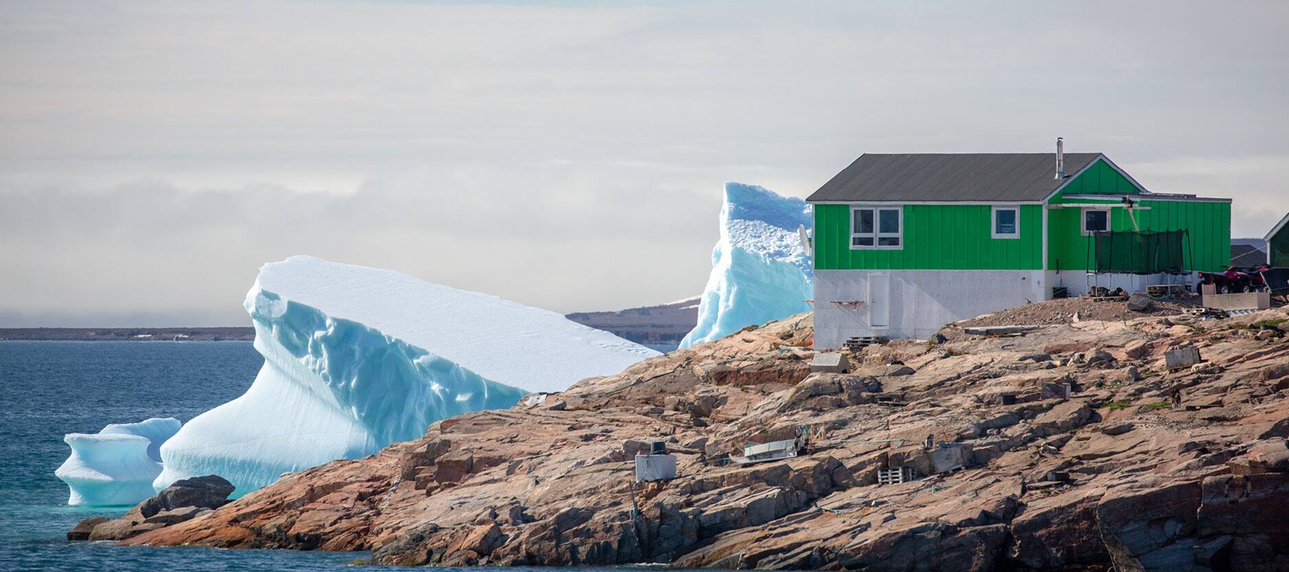 Observa las llamativas casas situadas en lo alto de una zona agreste con vistas al mar helado.