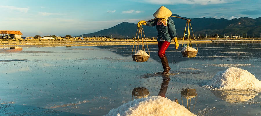 Mujer llevando sal de una granja de sal en Nha Trang